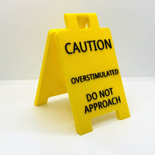 Load image into Gallery viewer, A yellow pop up sign for your desk that says "caution overstimulated do not approach".